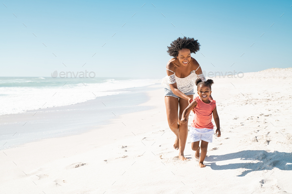 African mother running after her daughter on the beach