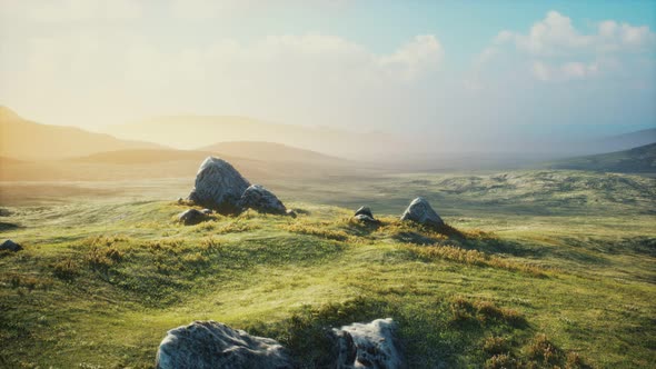 Meadow with Huge Stones Among the Grass on the Hillside at Sunset alt