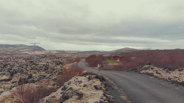 Young woman walking along countryside road alt