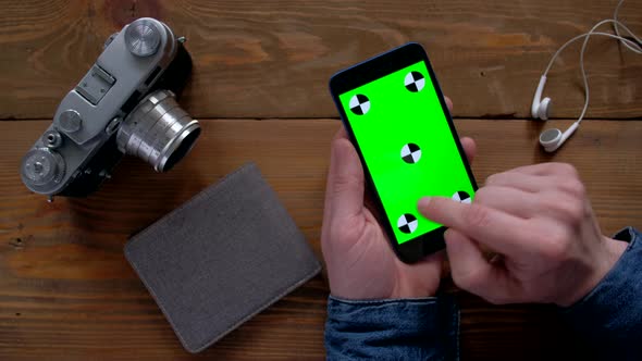 Photographer Using Smartphone  with Green Screen on Wood Table alt