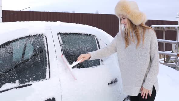 Young European Girl Cleaning Her Car From Snow