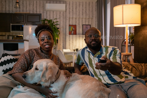 African couple with dog watching TV