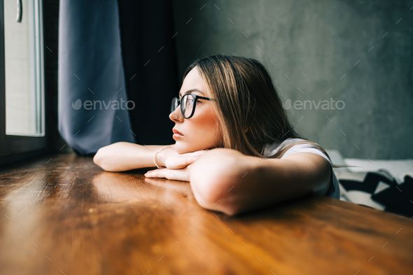 Young bored millennial woman looking at window alone at home - Stock Photo - Images