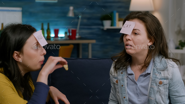 Group of multiethnic people playing interesting guess who game putting sticky notes on forehead