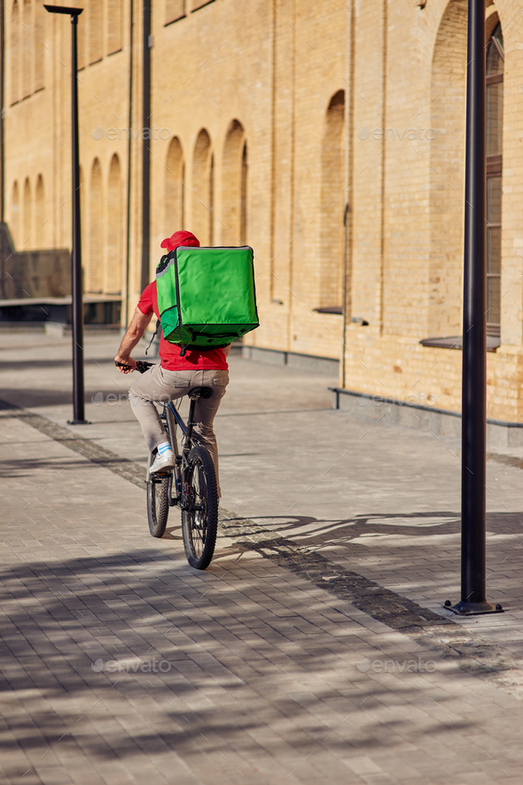 Delivery man with refrigerator bag riding bicycle