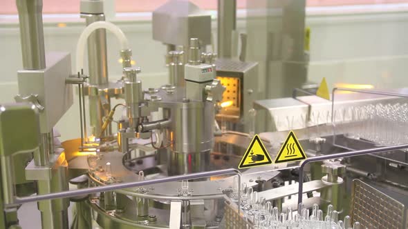 Total shot of glass medical being opened, filled and sealed by machine. alt