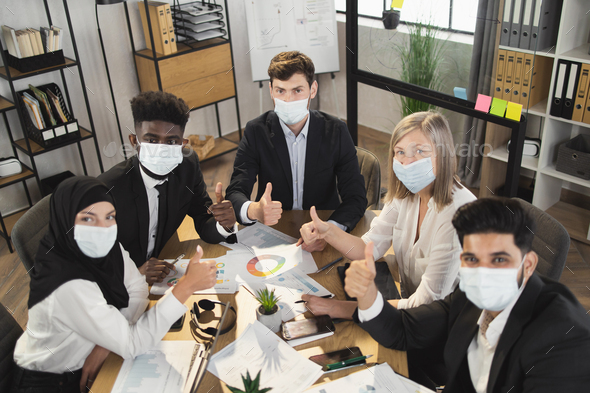 Company workers in masks fist bumping during meeting