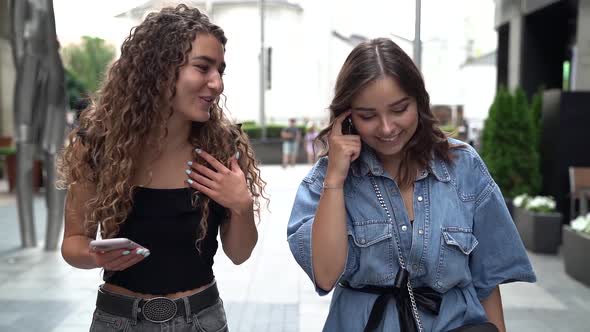 Close-up of Two Fun, Stylish and Friendly Young Women Walking Down a City Street Full of People and alt