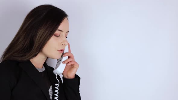 A young woman in a business suit answering the telephone and flirting romantically on the phone
