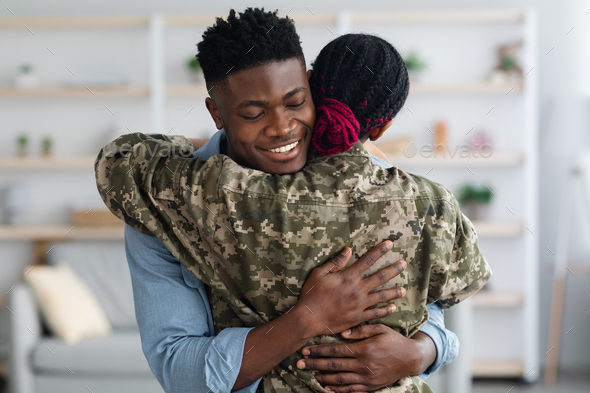 Happy black family military wife and husband embracing at home