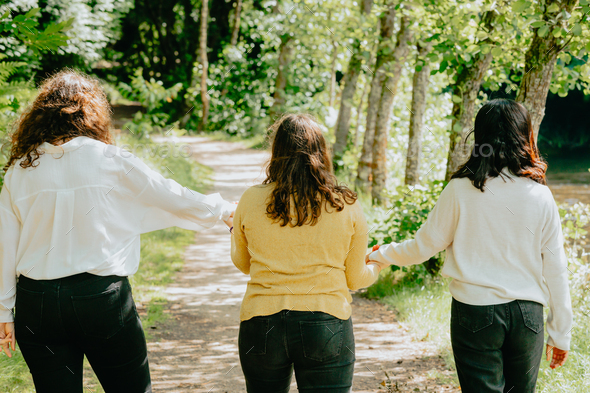Three young woman holding hands together walking to the future trough a path,