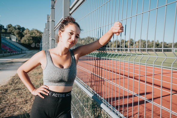 Young african woman next to a running pitch on sport clothes, urban sport  style, copy Stock Photo by AveCalvar