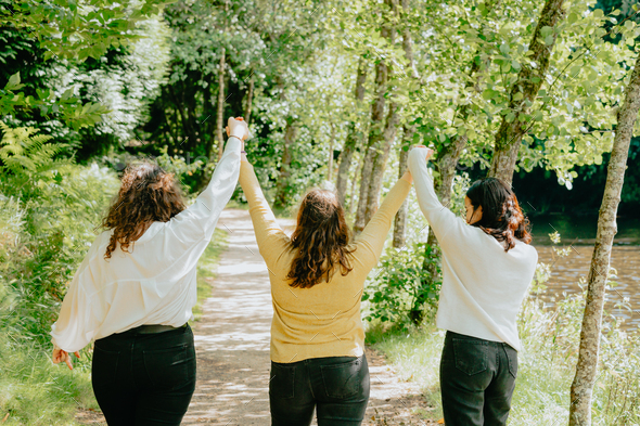 Three young woman holding hands together walking to the future trough a path