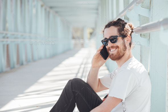 Young hipster man at the airport or bus station waiting while calls someone