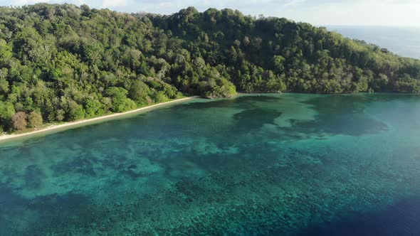 Aerial: flying over tropical Hatta island white sand beach Banda Islands Maluku alt
