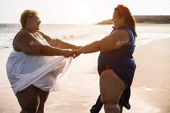 Curvy Women Dancing On The Beach Having Fun During Summer Vacation Focus On Faces Stock Photo