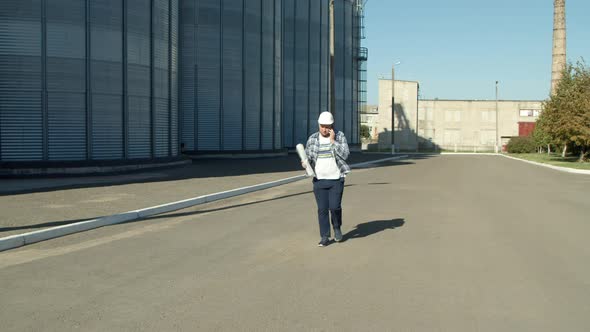 Professional Engineer with Blueprints Inspecting Agricultural Silos