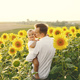 Father hugging his son while standing in the sunflowers field - PhotoDune Item for Sale