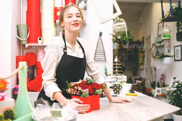 Portrait of pretty florist girl in flower shop. Seller at the counter of a flower boutique