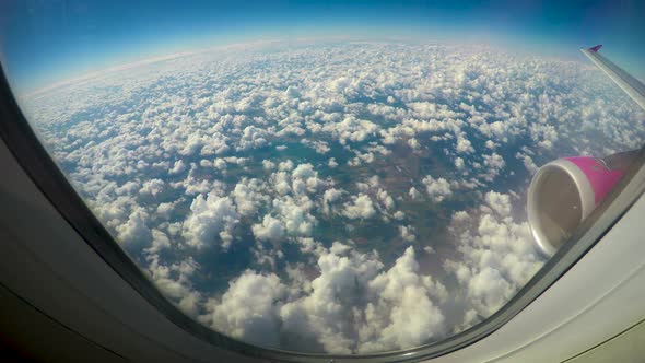 Fluffy clouds viewed from airplane windows, wing and turbine in shot, low cost alt
