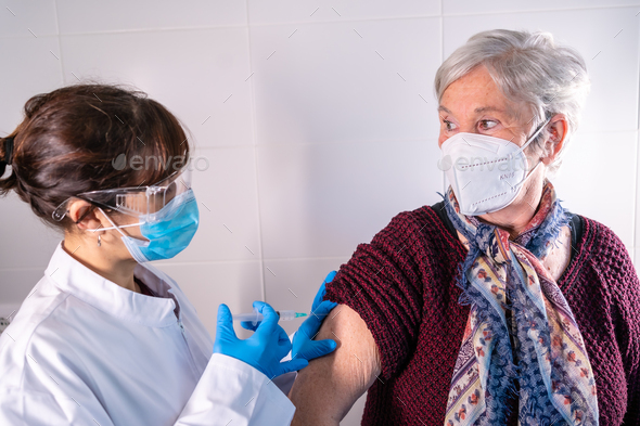Female doctor applying the coronavirus vaccine to an elderly lady.