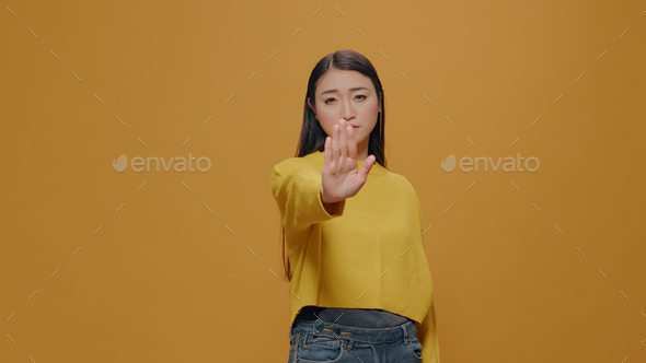 Asian woman doing rejection gesture with hand in front of camera