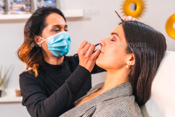 Makeup artist with face mask making up the client's face