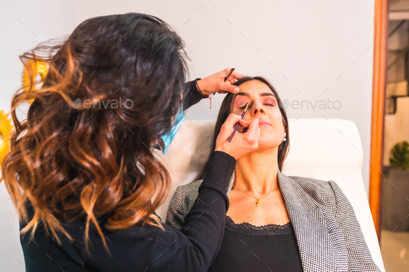 Makeup artist with face mask making up the client\'s face