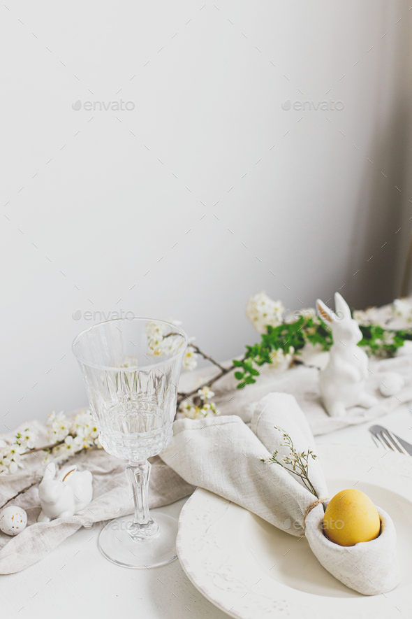 Stylish elegant Easter brunch table setting. Easter egg in bunny napkin on plate