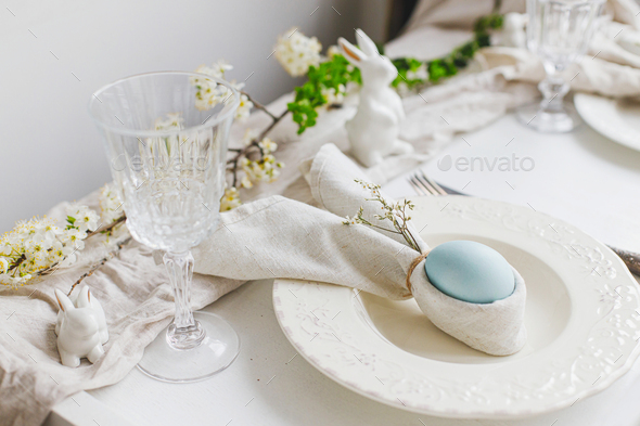 Stylish elegant Easter brunch table setting. Easter egg in bunny napkin on plate