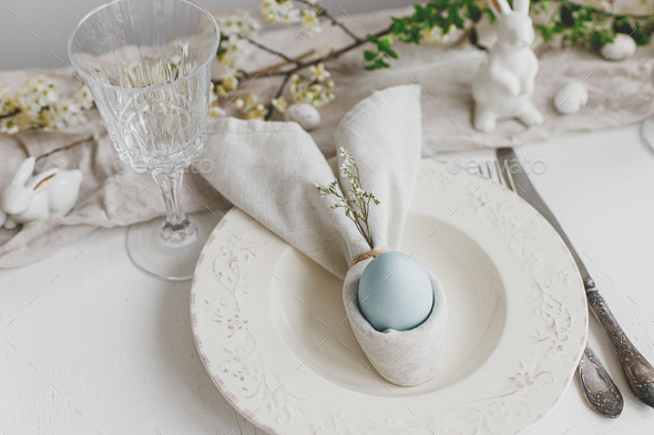 Happy Easter! Stylish elegant Easter brunch table setting. Easter egg in bunny napkin