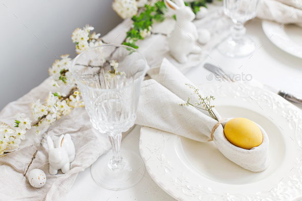 Happy Easter! Stylish elegant Easter brunch table setting. Easter egg in bunny napkin