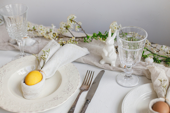 Easter egg in bunny napkin on plate with cutlery. Stylish elegant Easter brunch table setting