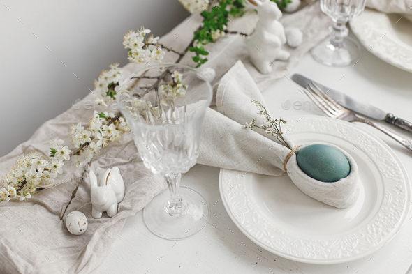 Stylish elegant Easter brunch table setting. Easter egg in bunny napkin