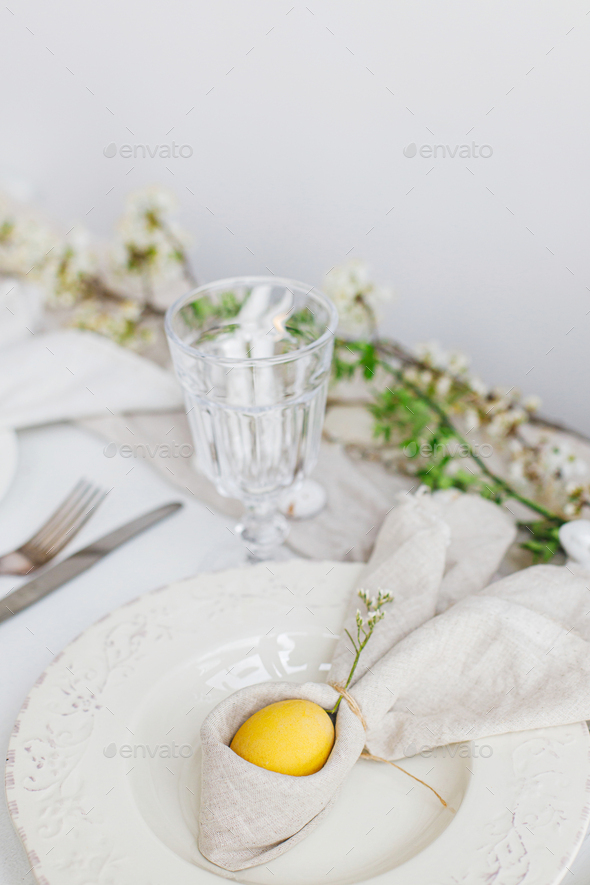Happy Easter! Stylish elegant Easter brunch table setting. Easter egg in bunny napkin on plate