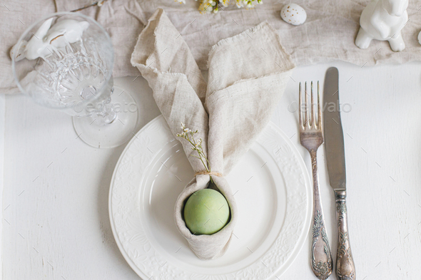 Happy Easter! Elegant Easter brunch table setting. Easter egg in bunny napkin on plate, top view