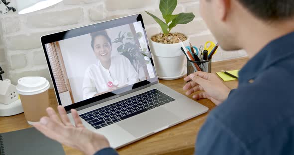 Young woman waving hand and talking on video call with colleague