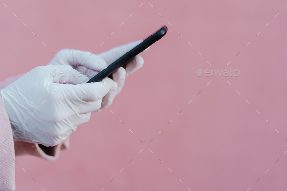 caucasian woman in the street wearing protective gloves and using mobile phone. corona virus concept