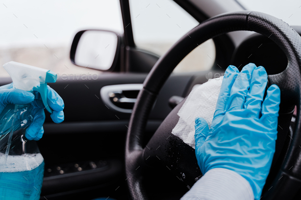 unrecognizable man in car using alcohol gel to disinfect steering wheel during pandemic