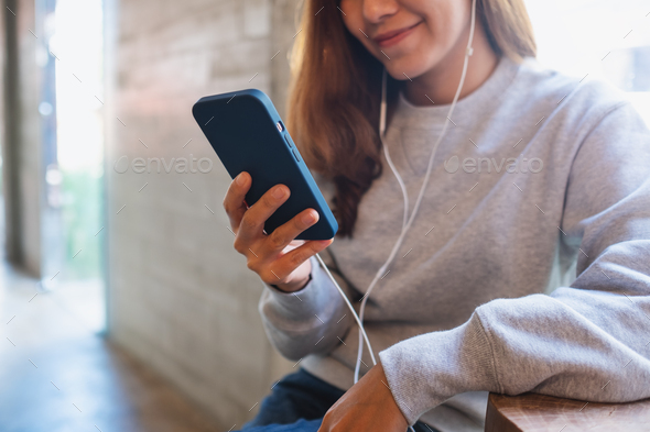 Closeup of a young woman using mobile phone for video call or listening to music