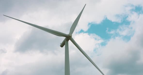 Slow motion wind turbine blades rotating against a cloudy background alt