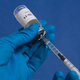 Hands in blue medical gloves drawing a syringe with covid-19 vaccine from a vial - PhotoDune Item for Sale
