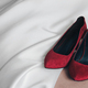 Wedding red velvet shoes of the bride on a white dress. - PhotoDune Item for Sale