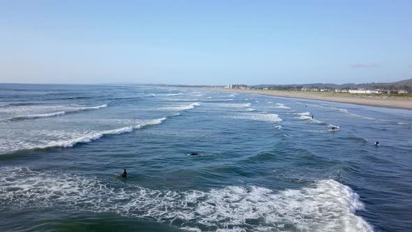 Aerial view of many surfers in the water catching waves in the Pacific Ocean. alt