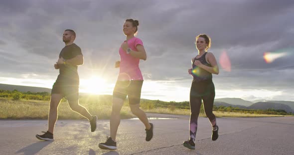 Multiethnic Group of Athletes Running Together on a Panoramic Countryside Road alt