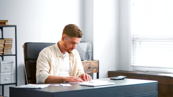 Male manager assistant with beard in yellow shirt sorts small receipts alt