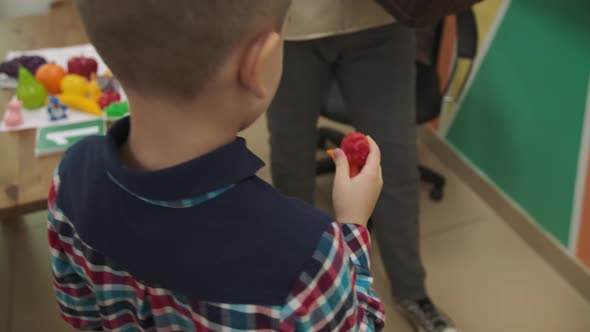 An African American Teacher and a Group of Children are Studying Fruits and Animals in the Classroom alt