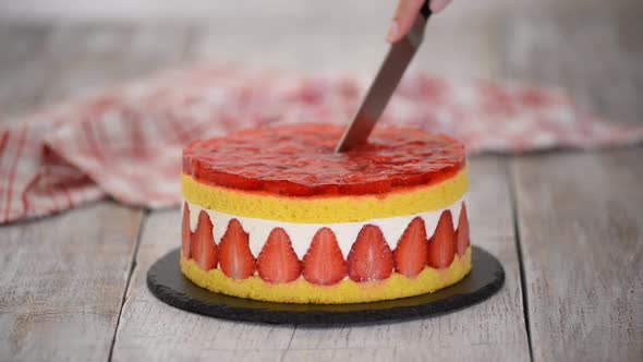 Cutting fresh baked cake with strawberry jelly topping.