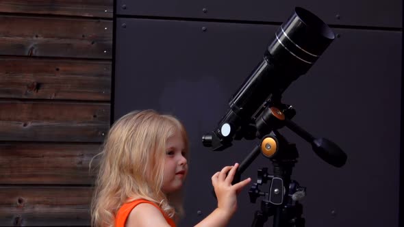 A Little Girl is Looking in a Telescope on a Summer Day alt