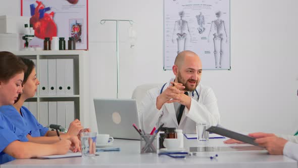 Specialist Doctor Sitting on Conference Desk Discussing with Team alt